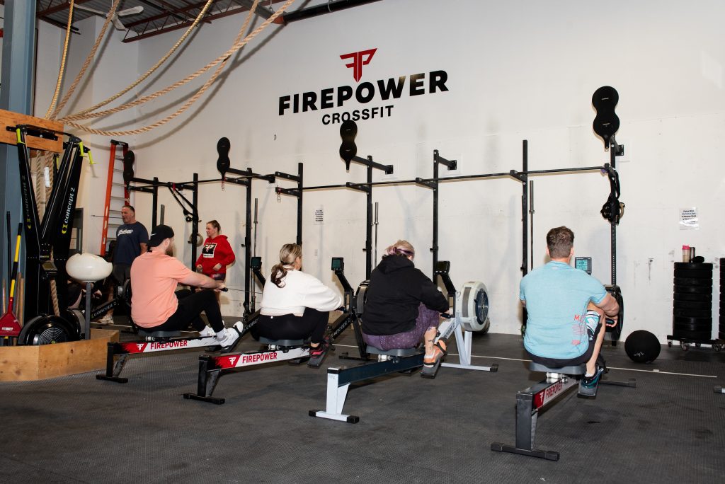 Members rowing hard during a CrossFit workout